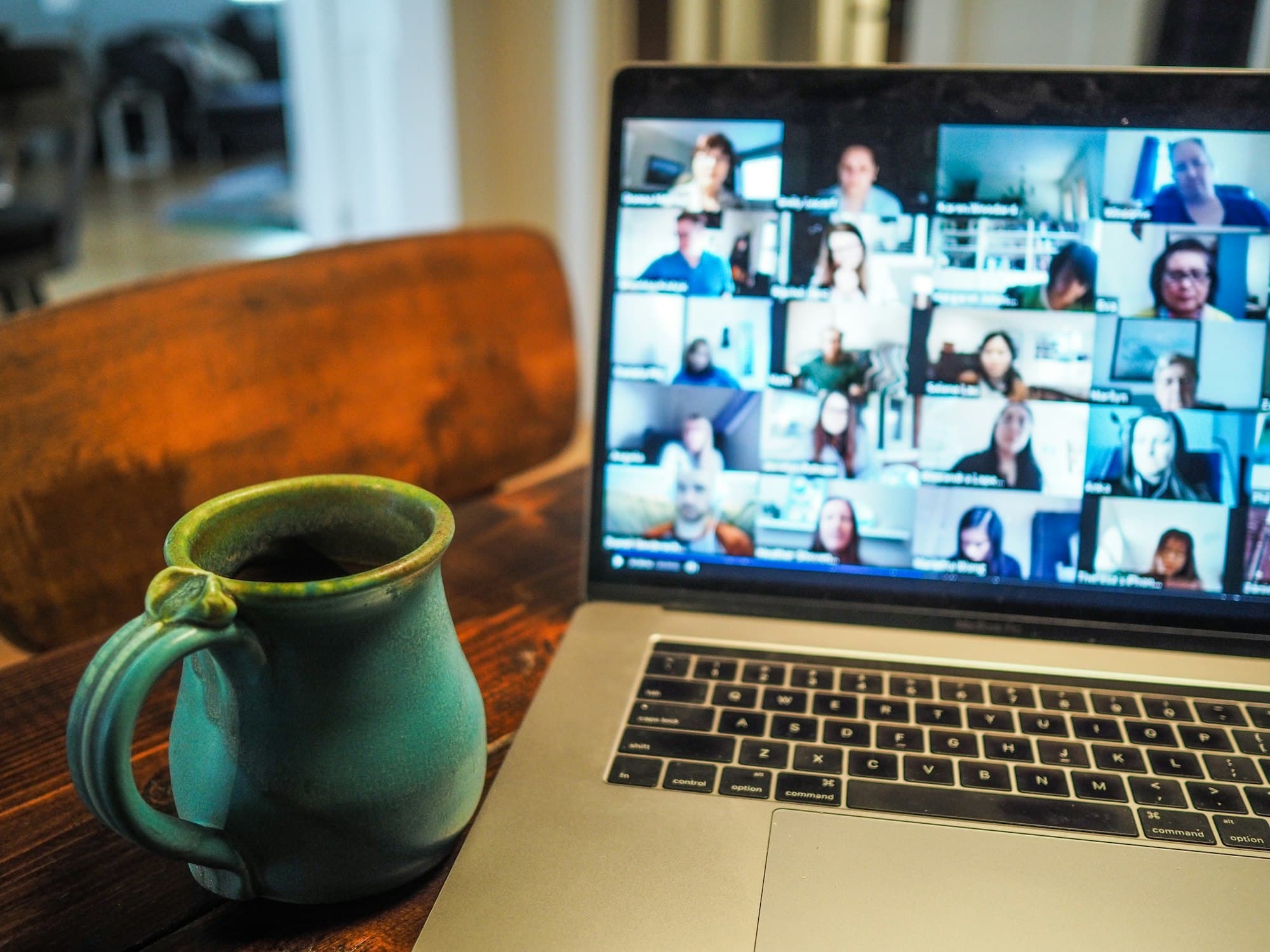 A laptop showing a video call next to a coffee mug