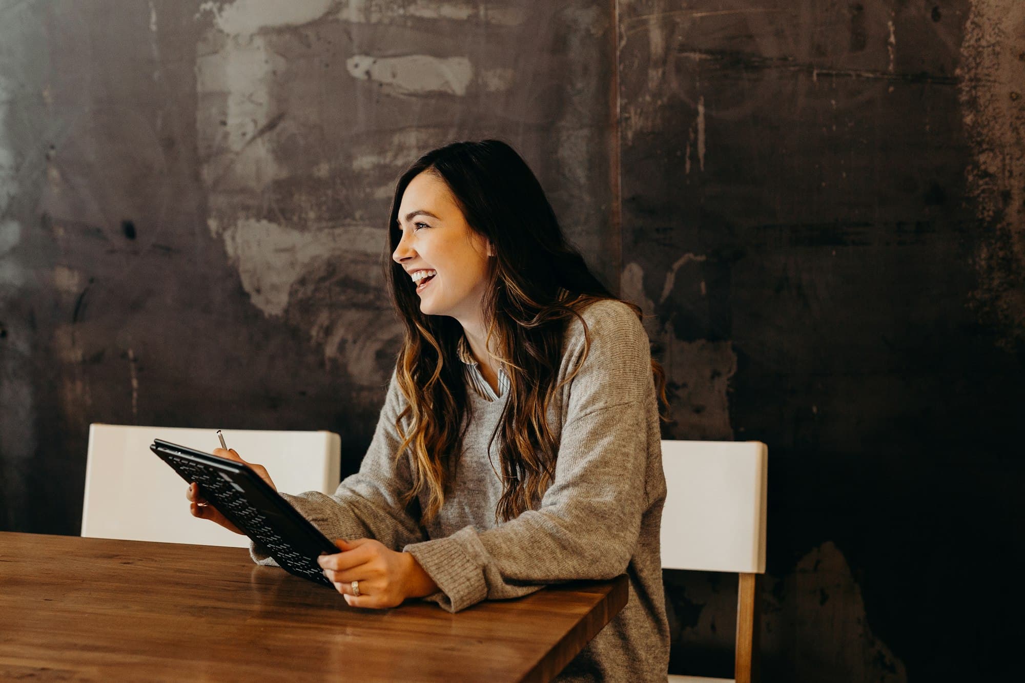 A woman smiling during a video session on her tablet at home