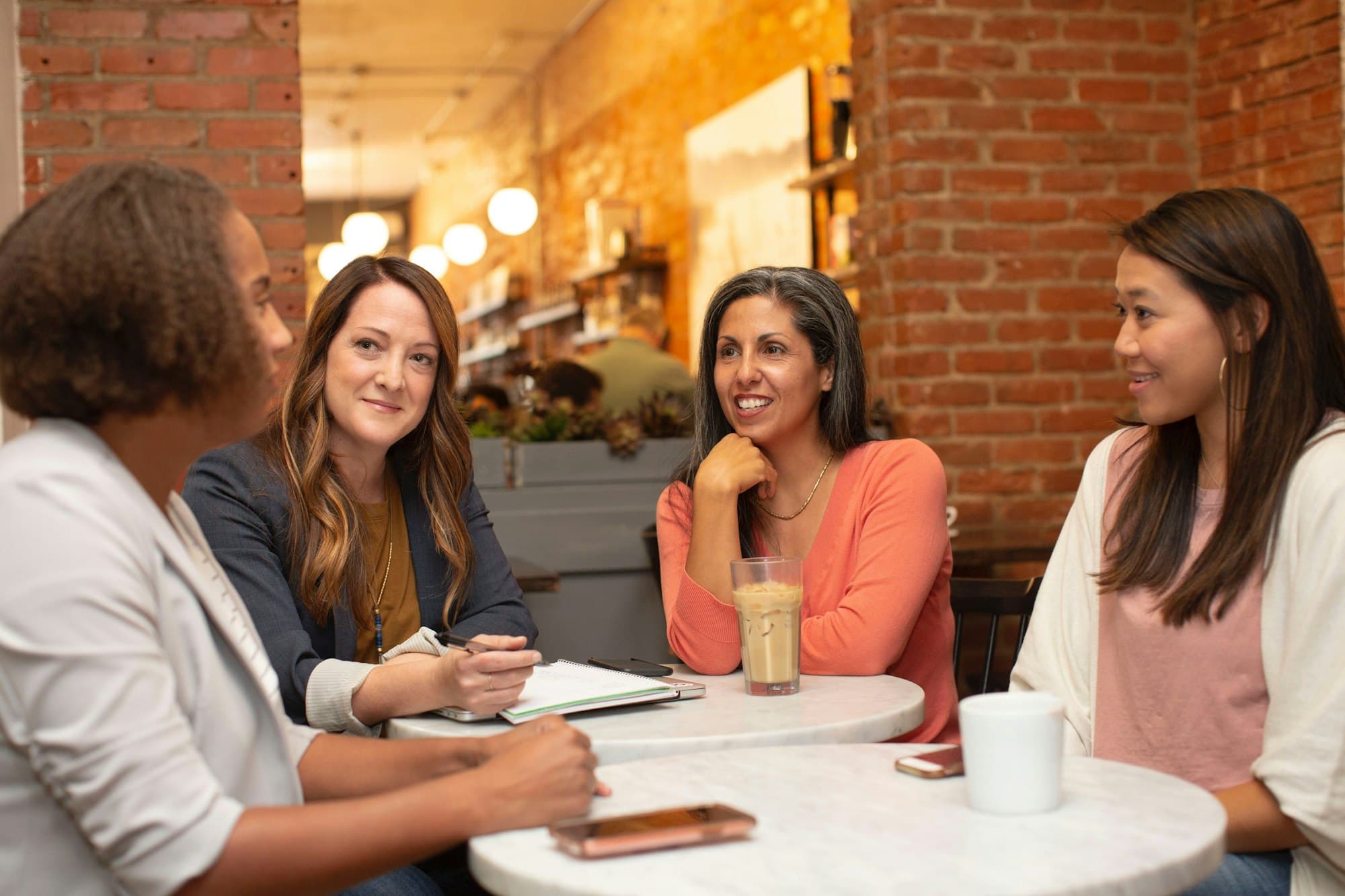 Four women talking and laughing together around a café table